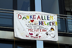 Plakat mit Aufschrift Danke allen Helfern, die ihren Dienst leisten, damit unsere Gemeinschaft diese Situation meistern kann