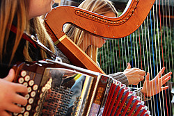 Zwei Frauen spielen Harfe und Ziehharmonika 