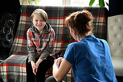 Lachendes Kind auf Couch unterhält sich mit einer Frau