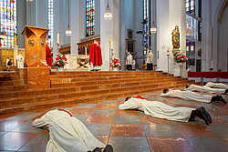 Männer liegen auf dem Bauch vor dem Altar, Kardinal Reinhard Marx steht mit dem Rücken zu ihnen
