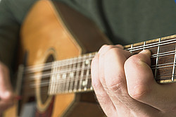 Hand auf Gitarrensaiten in Großaufnahme