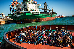 Migranten sitzen an Deck des Schiffes William Butler Yeats der irischen Marine bei dessen Ankunft im Hafen von Augusta (Sizilien).