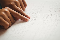 Hände gleiten über ein Blatt mit Blindenschrift