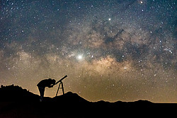 Person schaut durch Teleskop in den Sternenhimmel