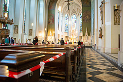 Blick in Kirche mit Absperrbändern vor manchen Kirchenbänken