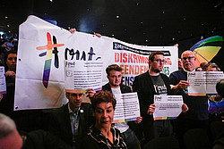 Menschen halten ein Banner und Plakate hoch während der Verleihung des Katholischen Medienpreises 2022