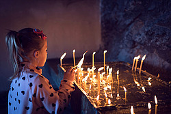 Kind entzündet Opferkerze in Kirche