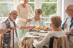 Senioren sitzen am Tisch und essen Kuchen