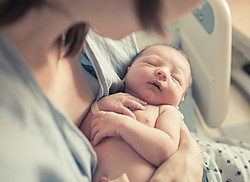 Mutter mit Baby im Arm im Krankenhausbett